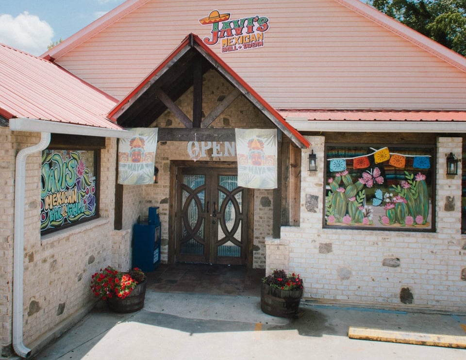 Exterior of Jay's Mexican restaurant with colorful murals, brick walls, and an open sign above the entrance.